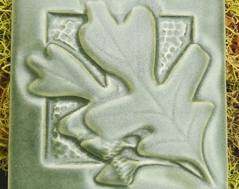 Azulejo artesanal de estilo Misión con diseño de hoja de roble y bellota.