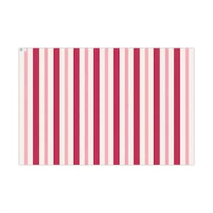May include: A rectangular sheet of paper featuring a repeating vertical striped pattern. The design consists of alternating stripes in shades of deep magenta, soft light pink, and off-white, creating a consistent and uniform linear graphic.