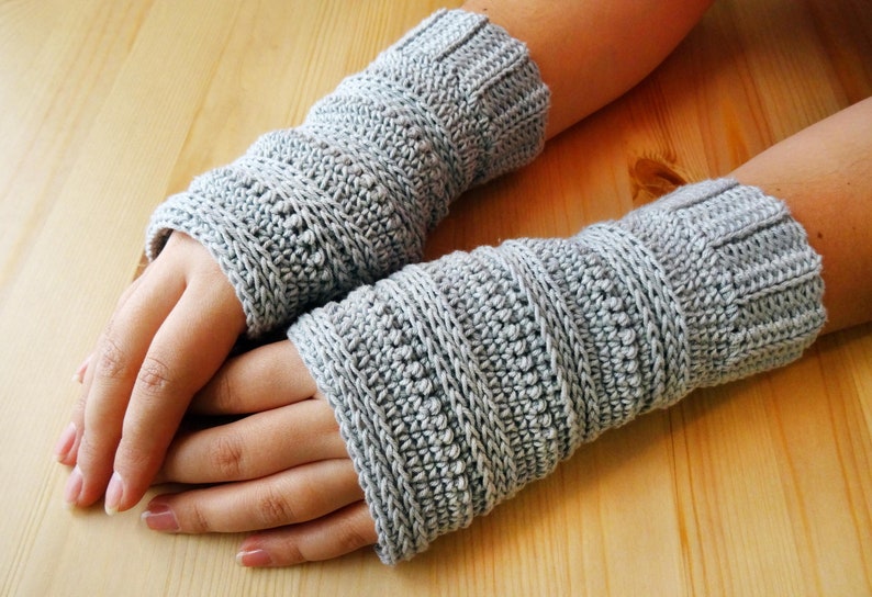 May include: Two gray crocheted fingerless gloves with a textured pattern.