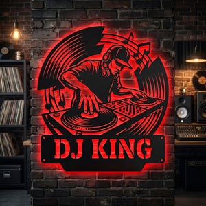 May include: A black metal wall sign featuring a silhouette of a DJ wearing headphones and operating a turntable, with musical notes and circular patterns. The sign is backlit with red light and displays the text DJ KING at the bottom.