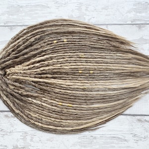 Könnte beinhalten: Ein Set langer, brauner und blonder synthetischer Dreadlocks mit goldenen Perlen.