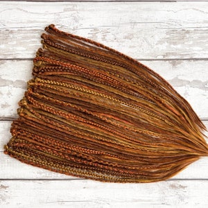 May include: A bundle of brown, blonde, and orange synthetic hair extensions. The extensions are braided and ready to be installed.