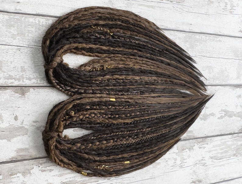 Close-up of dark & light brown synthetic dreadlocks, crafted with precision for a natural look. Featuring a mix of criss-crossed wraps, braids, and plaits, these lightweight loc extensions are washable and reusable. Designed for effortless styling, they offer a soft, flexible feel and a