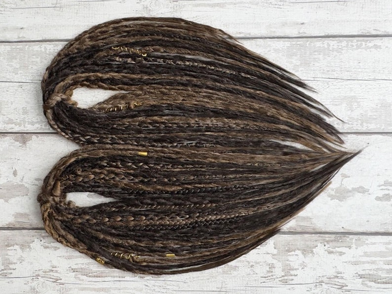 Flat layout of DE dreads highlighting variation in thickness and length. Handmade twist-sealed synthetic dreads, customizable to longer or shorter lengths. SE version also offered. Great for hair transformation, dread installs, partial or full-head styles.