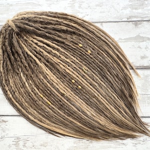 May include: A set of brown and blonde synthetic dreadlocks with gold beads.