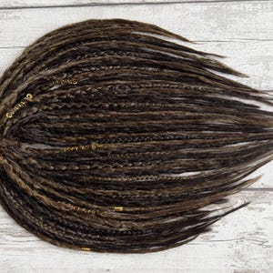 Premium-quality crochet dreadlocks in brown tones, displayed in a neatly arranged bundle. These synthetic loc extensions mimic the natural dreadlocked appearance with detailed braiding and hand-wrapped elements. Available in multiple sizes, perfect for achieving a full-head dread look or adding accent pieces.