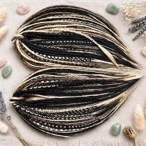May include: A set of synthetic hair extensions arranged in a heart shape, featuring a blend of black, dark brown, and platinum blonde strands. The extensions include a mix of smooth fibers, twisted locks, and braided textures throughout the bundle.