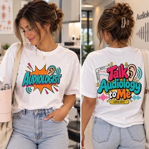 May include: A white t-shirt featuring a colorful graphic on the front that reads AUDIOLOGIST in teal letters. The back displays the text Talk Audiology to Me with an ear illustration, a hearing test chart, and sound wave graphics.