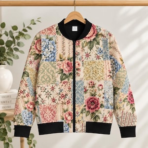 May include: A bomber jacket featuring a patchwork design of various floral patterns in shades of pink, blue, green, and cream. The jacket has a black ribbed collar, black cuffs, a black hem, and a central black zipper closure down the front.