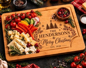 Op de afbeelding: Een rechthoekige serveerplank van bamboe met de gravure THE HENDERSONS Merry Christmas EST. 2026, voorzien van dennenboom- en bladerpatronen. De plank is belegd met kerstomaatjes, gesneden paprika, komkommer, radijs en kaasblokjes.