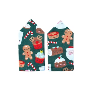 May include: Two fabric oven mitts with a pointed top, featuring a dark green background printed with a repeating pattern of gingerbread people, cupcakes, candy canes, and holiday treats with smiling faces in red, white, and brown colours.