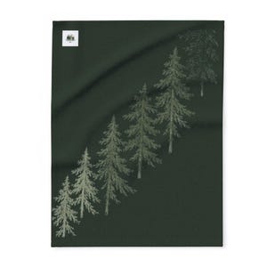May include: A dark forest green rectangular fabric piece featuring a diagonal pattern of six light green pine trees. The trees are arranged in a line from the bottom left to the top right. A small white square label is visible in the top left corner.