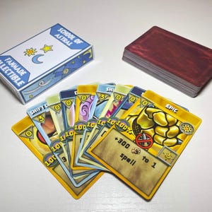 Peut inclure: Un jeu de cartes à collectionner fanmade School of Astral comprenant une boîte blanche avec du texte bleu et des icônes célestes, un paquet de cartes aux dos rouge foncé et un éventail de cartes de jeu avec des bordures jaunes et le mot Epic.
