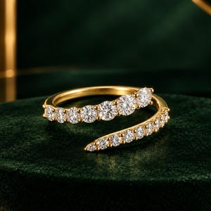 Könnte beinhalten: Ein Goldring im Bypass-Design mit zwei überlappenden Reihen aus runden, im Brillantschliff geschliffenen weißen Diamanten. Der Ring besteht aus poliertem Gelbgold, wobei die Diamanten entlang des offenen Spiraldesigns gefasst sind.