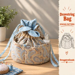 Puede incluir: Una bolsa de tela con cordón con un patrón de cachemira en tonos beige y azul y un forro floral azul. La bolsa tiene una base circular, cierre de cordón y un pequeño botón azul en la parte delantera. El texto a la derecha dice Drawstring Bag SEWING PATTERN SwngptrnGoods.