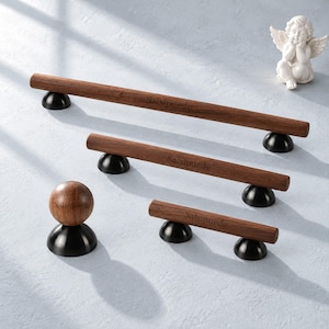 Puede incluir: Un conjunto de tres tiradores de armario de madera y un pomo de armario de madera, cada uno con un acabado de veta de madera marrón oscuro, bases de montaje circulares negras y la palabra Salsipuede grabada en la superficie de la madera.
