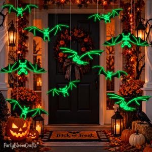 May include: A collection of hanging neon green skeleton bat decorations suspended in front of a dark door with a wreath. The bats feature glowing skeletal structures and outstretched wings, creating a festive Halloween display with pumpkins.