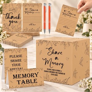 May include: A memory box set featuring a tan cardboard box with black text reading Share a Memory, matching cards with floral borders, and two orange pens. The cards include the text Share a Memory or words of love with love and thank you.