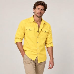 May include: A bright yellow long-sleeve button-down shirt featuring a classic collar, two chest pockets with buttoned flaps, and a front button placket. The shirt is paired with light tan trousers, creating a clean and simple ensemble.