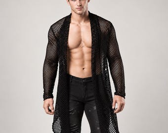 May include: A black long-sleeved open-front cardigan featuring a mesh net construction. The garment has a knee-length hem and is worn over black distressed denim jeans. The cardigan is made of a lightweight, semi-sheer fabric with a diamond pattern.