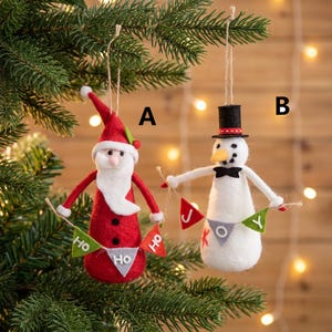 Può includere: Due decorazioni natalizie in feltro appese a uno spago. La decorazione A è un Babbo Natale in abito rosso che regge uno stendardo verde, bianco e rosso con la scritta HO HO HO. La B è un pupazzo di neve bianco con cilindro nero e scritta JOY.