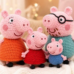 Pode incluir: Um conjunto de quatro bonecos de porco feitos de crochê com cabeças de fio rosa e traços faciais bordados. O porco maior veste uma camisa azul-petróleo e óculos pretos, outro um vestido laranja, um um vestido vermelho e o menor uma camisa azul.