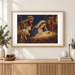 May include: A framed diamond painting depicting a nativity scene with a central figure holding a baby in a manger, flanked by two figures in robes, one holding a staff and a small white lamb, all rendered in a pixelated grid pattern.