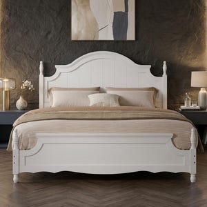 May include: A white wooden bed frame featuring a tall, arched headboard with vertical paneling and matching footboard with turned post details. The bed is dressed with a neutral-toned comforter, two large pillows, and a small decorative throw pillow.
