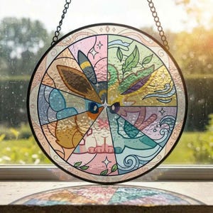 May include: A circular stained glass suncatcher featuring a segmented design with various pastel-colored illustrations of creatures. The piece is framed in a thin black metal border and hangs from a black chain, displaying intricate line work and patterns.