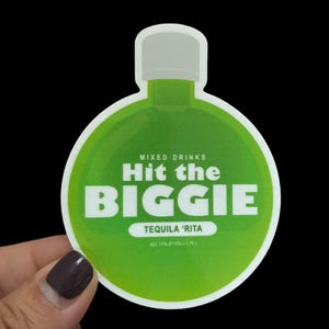 May include: Green round sticker with a white outline, shaped like a bottle. The sticker says "MIXED DRINKS Hit the BIGGIE TEQUILA 'RITA ALC 15% BY VOL - 1.75 L"