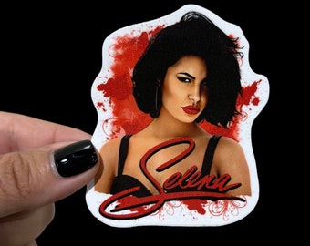 May include: A sticker featuring a portrait of Selena, a famous singer, with a red and white background. The sticker has a red, white, and black color scheme and features a stylized signature of "Selena" in red.
