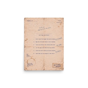 May include: A rectangular piece of aged, tan paper with visible creases and a coffee stain. It features the text writing manifesto, a numbered list of six points, and handwritten notes in blue ink, including the phrase let it remain unfinished.