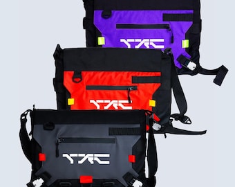 May include: Three messenger bags in black with purple, red, and gray front panels. Each bag features a horizontal zippered pocket, a white logo, side release buckles, and adjustable straps. The gray bag displays the text CRX/TYPE-03.