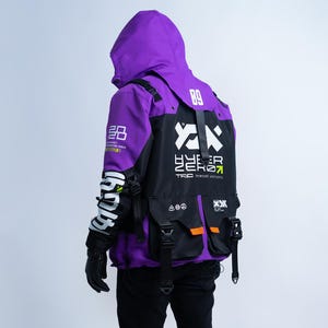 Puede incluir: Una chaqueta con capucha morada y negra que presenta texto gráfico en blanco que incluye 89, 2020 y HYPER ZERO. La chaqueta tiene múltiples bolsillos utilitarios con correas y hebillas negras, junto con caracteres japoneses blancos en las mangas.