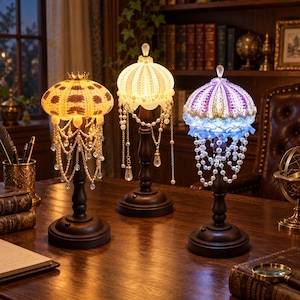 May include: Three table lamps with dark brown bases and shades shaped like sea urchins. The left lamp glows yellow, the centre lamp glows white, and the right lamp glows purple and blue. Each shade is adorned with hanging pearl-like beads.