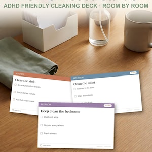 Può includere: Un set di Home Reset Cards con un mazzo per le pulizie adatto all'ADHD con compiti stanza per stanza. Sono mostrate tre carte: una carta cucina color terracotta, una carta bagno blu e una carta camera da letto viola.