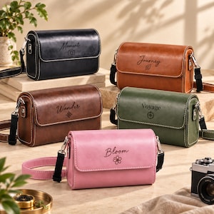 Pode incluir: Cinco bolsas tiracolo retangulares em preto, castanho, castanho escuro, verde azeitona e rosa. Cada bolsa tem uma aba com costura branca, alça removível e uma palavra única com ícone: Moment com câmara, Journey com folha, Wander com bússola, Voyage com bússola e Bloom com flor.