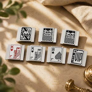 May include: Seven rectangular metal pins featuring graphic designs. The top row shows three skull motifs with the text 2099. The bottom row displays a red King of Hearts, a black King of Hearts, an Ace of Spades, and a pin with the text LATE VIP.