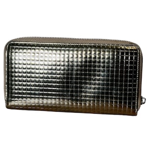 May include: A metallic silver wallet with a textured, grid-like pattern. The rectangular wallet has a zipper closure and a small silver pull. The overall design is sleek and modern, suitable for carrying essentials.