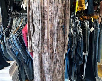 May include: A pink and black tweed skirt suit with a jacket featuring flap pockets and a skirt with a straight silhouette.