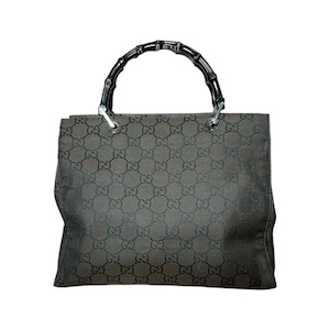 May include: A brown tote bag with a repeating pattern of the letters "G" and "O". The bag has a bamboo handle and silver-colored hardware. The bag is rectangular in shape.