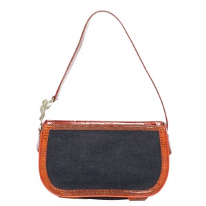 May include: A brown leather handbag with a denim flap and a gold clasp. The bag has a long strap.