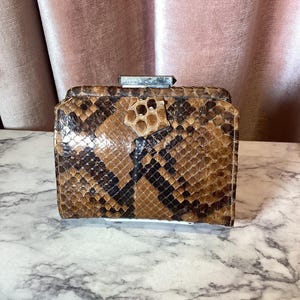 May include: A brown and black snakeskin wallet with a silver clasp.