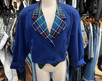 May include: A blue cropped jacket with a plaid collar. The jacket has a double breasted closure and long sleeves.