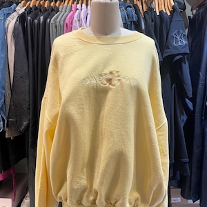 May include: A yellow sweatshirt with a white embroidered logo that says "GAP GOOD" on the front.