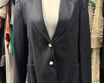 May include: A black blazer with two white buttons and two pockets. The blazer is on a mannequin in a clothing store.