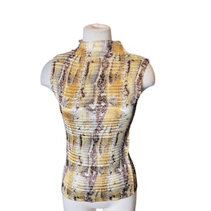 Może przedstawiać: Bezrękawnik z wysokim kołnierzem, z wzorem wężowej skóry w odcieniach brązu, złota i kremu. Tkanina ma prążkowaną fakturę. Top jest prezentowany na białym manekinie.