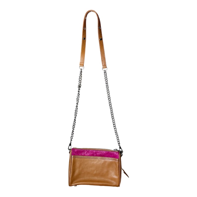 Puede incluir: Un bolso bandolera de cuero marr&oacute;n con un panel de ante rosa. El bolso tiene una correa de cadena y un asa superior de cuero marr&oacute;n. El bolso tiene un cierre de cremallera y una peque&ntilde;a borla.