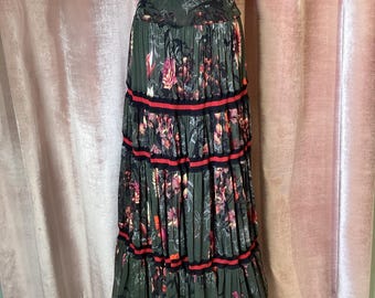 May include: A long, tiered skirt with a floral print in shades of green, pink, and black. The skirt has a high waist and is made of a lightweight fabric.