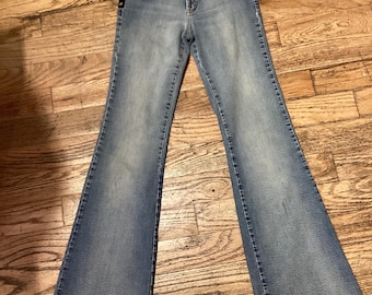 May include: Light blue denim jeans with a flared leg and studded detailing on the sides.